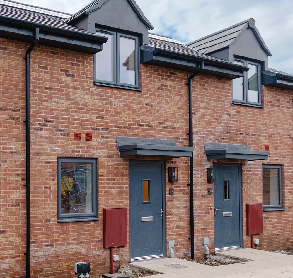 Newly build affordable homes - red brick with grey front doors and windows at Pear Trees in Leckhampton